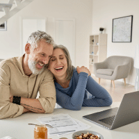Middle aged couple looking at computer screen to represent peace of mind in using financial advisor.