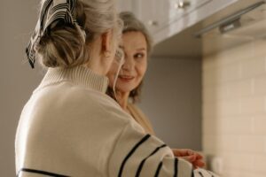 Two senior women having a joyful conversation in a cozy kitchen setting.